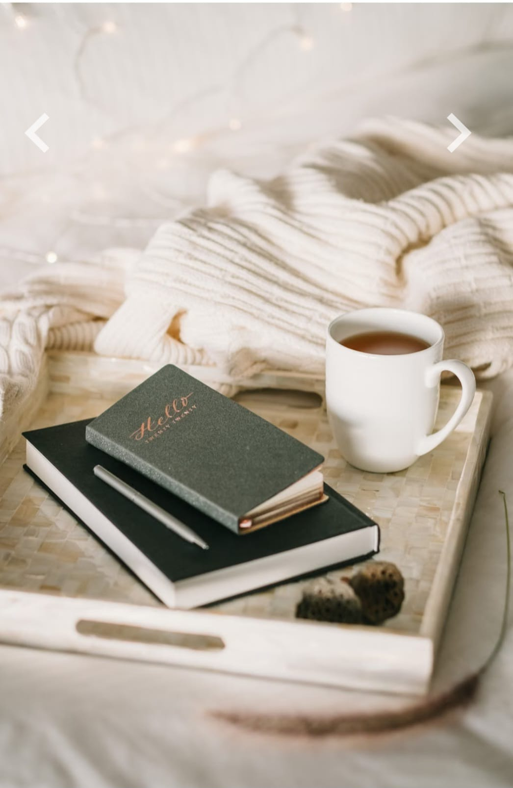 Plateau avec une tasse de thé, des carnets et une grosse maille, ambiance douce et reposante